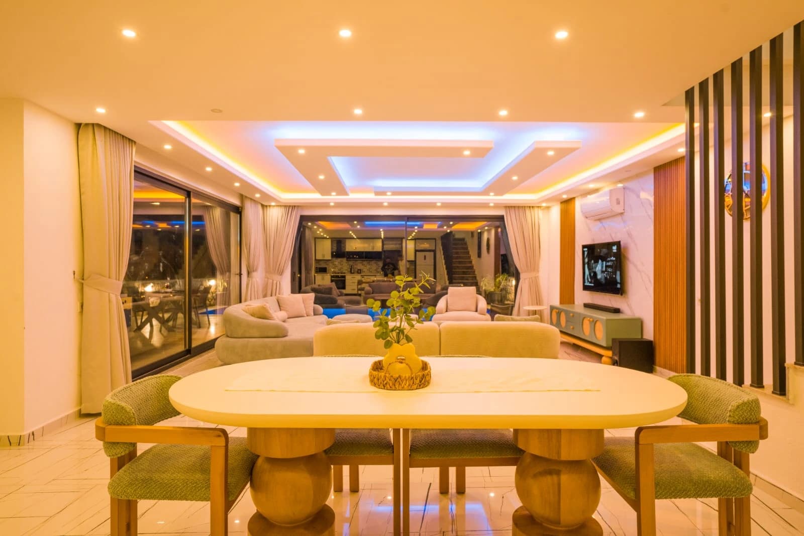 Spacious open-plan living area with elegant sofas and dramatic LED ceiling lighting.