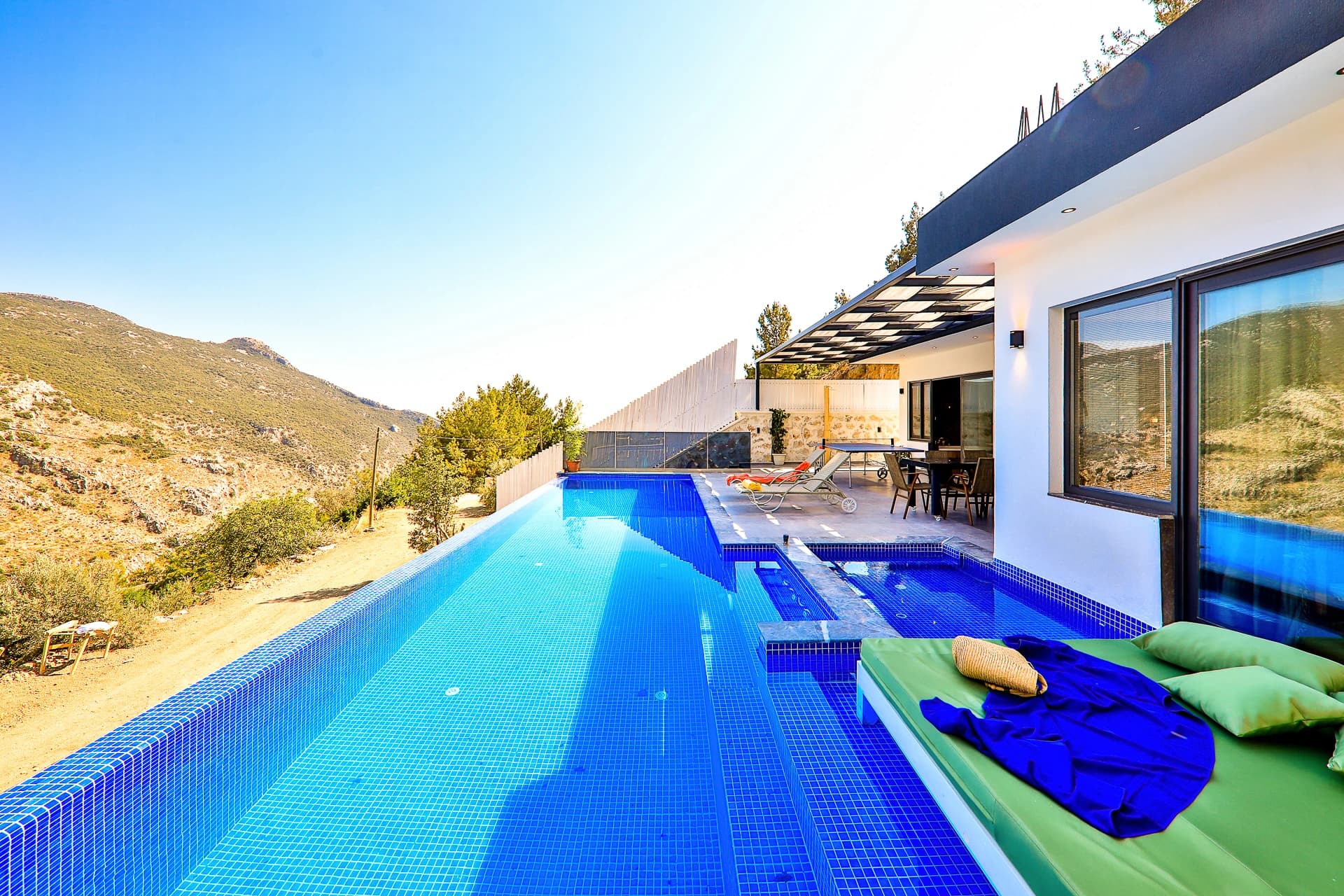 Expansive private pool with adjoining spa, sun loungers, and mountain vistas from the modern terrace.