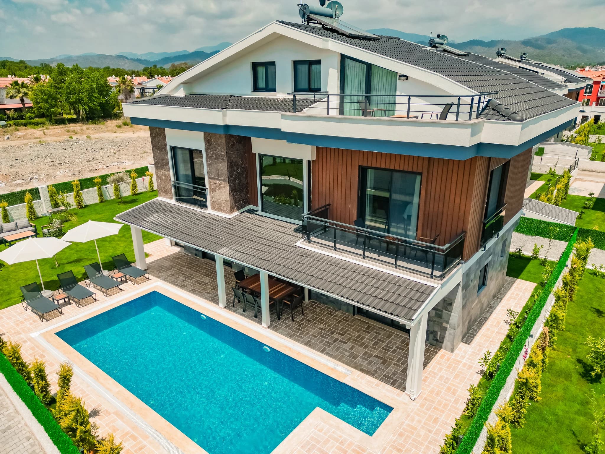 Spacious modern living room with dual velvet sofas, slate feature wall, smart TV, and garden access.