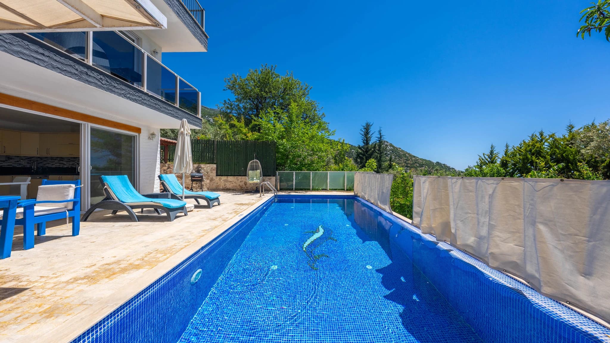 Private rectangular pool with sun loungers overlooking landscaped garden and mountains.