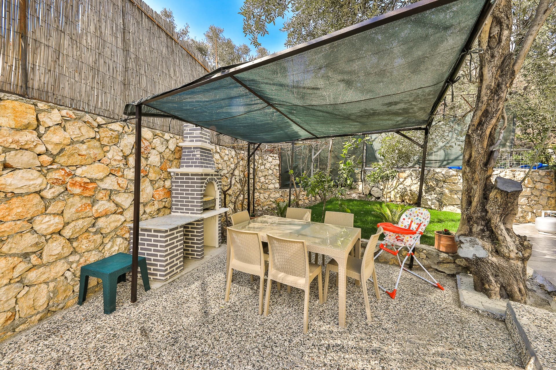 Shaded outdoor dining area with fireplace and stone architecture in the garden.