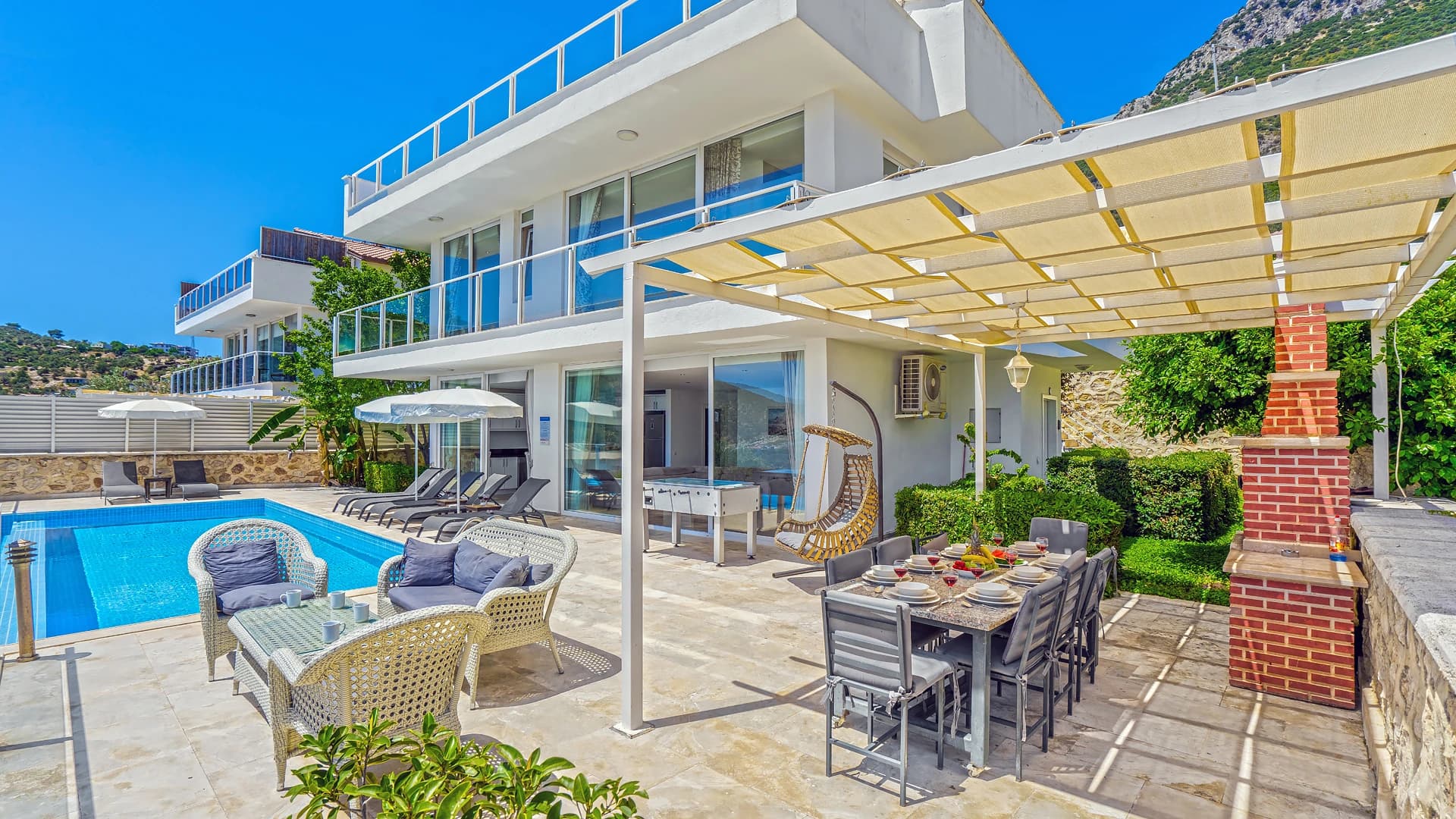 Expansive pool terrace with dining and lounge areas overlooking the coast.