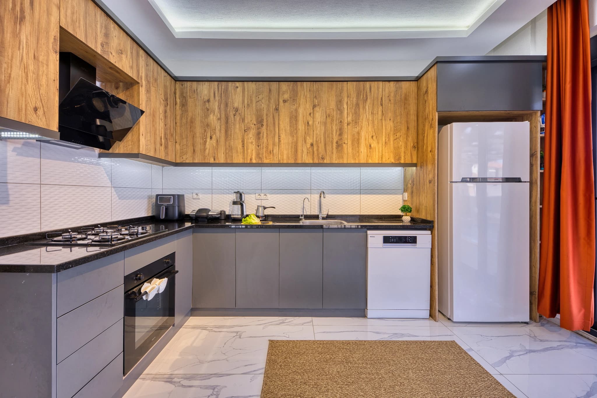Modern kitchen with gas cooktop, dishwasher, and wood cabinetry.
