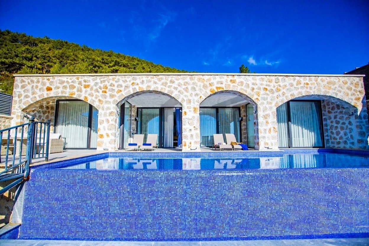 Luxury infinity pool with pristine blue tiles and traditional stone building design.