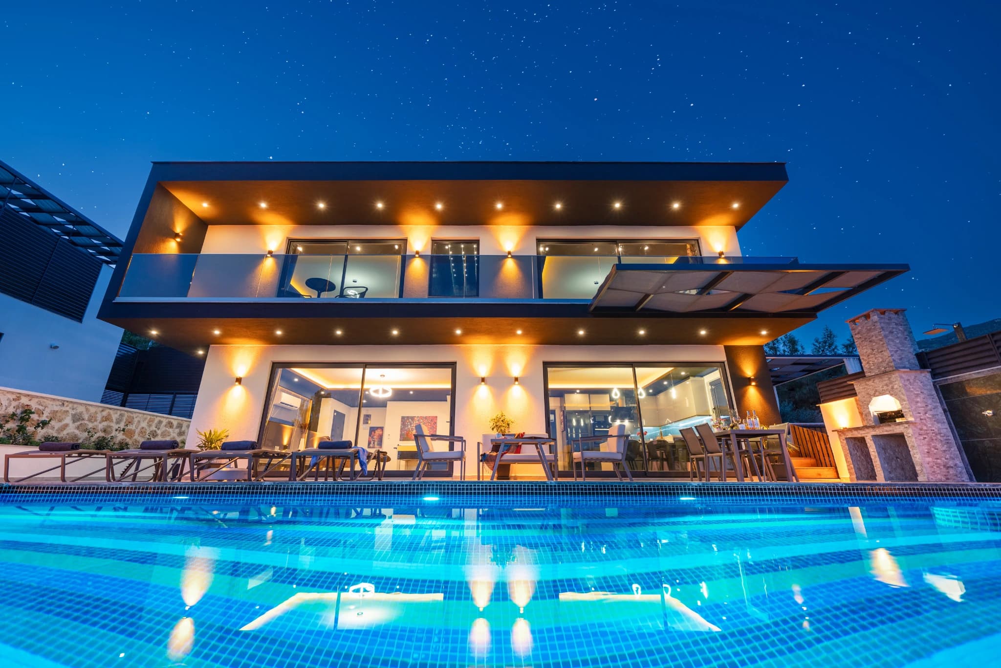 Stunning illuminated private pool with modern villa facade at twilight.