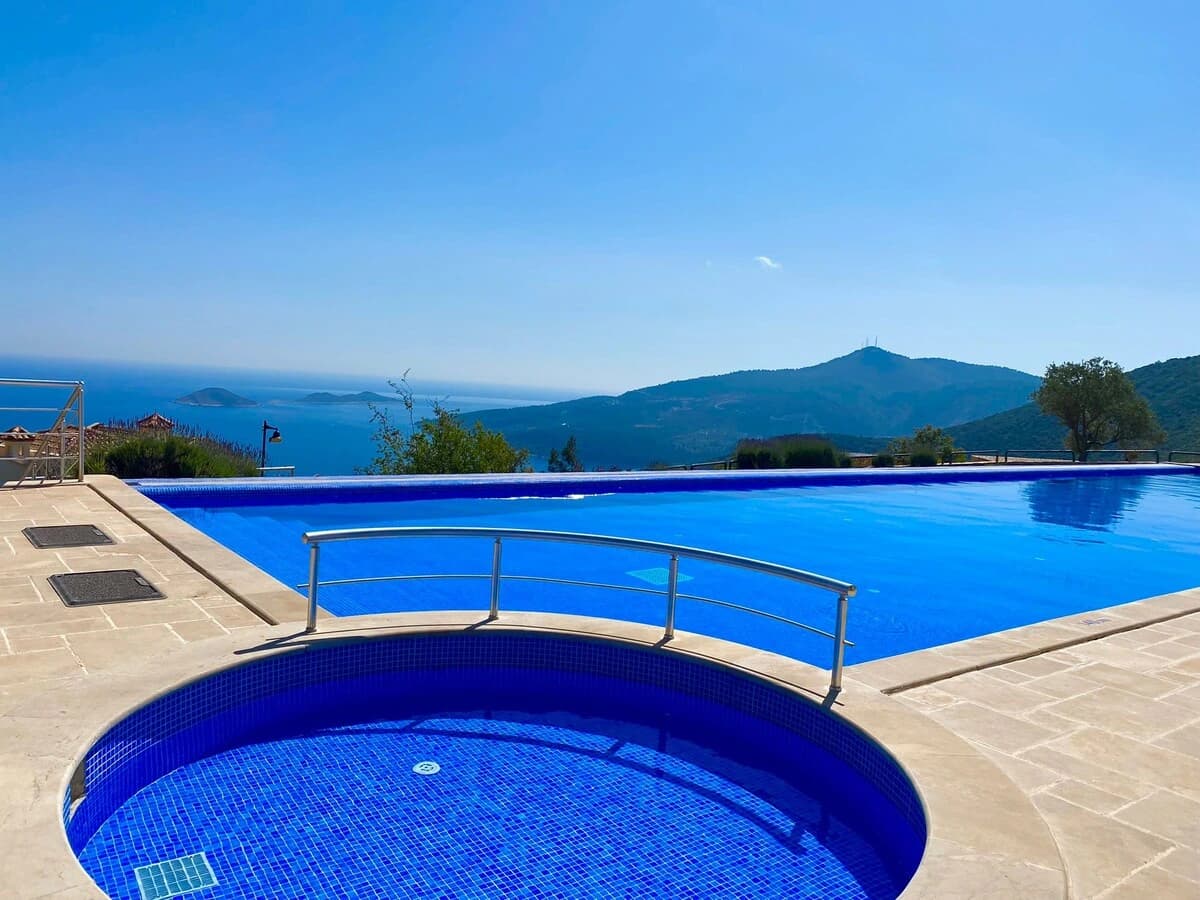 Large swimming pool with integrated jacuzzi overlooking scenic coastal landscape.