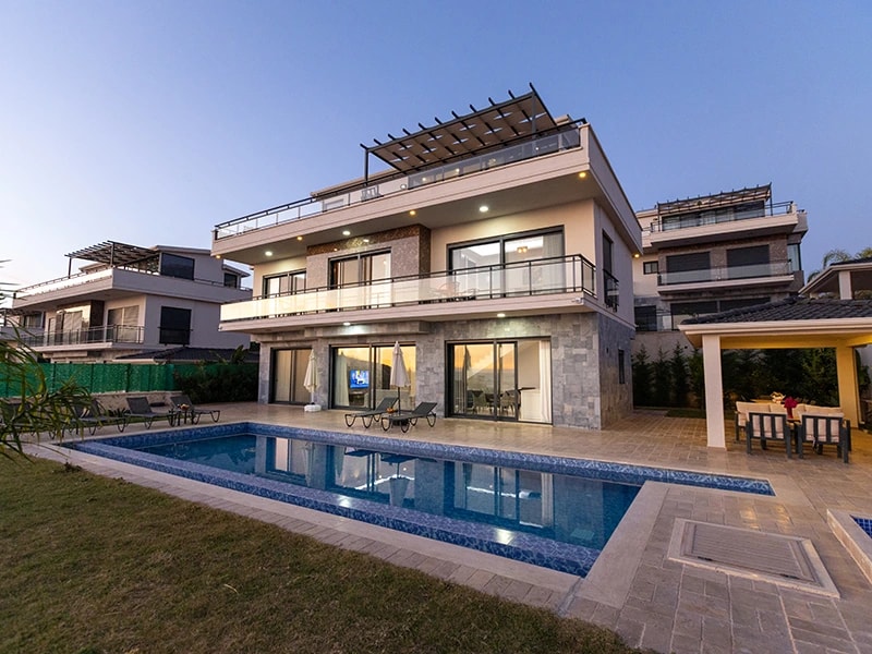 Evening view of the villa's exterior with illuminated private pool and terrace area.