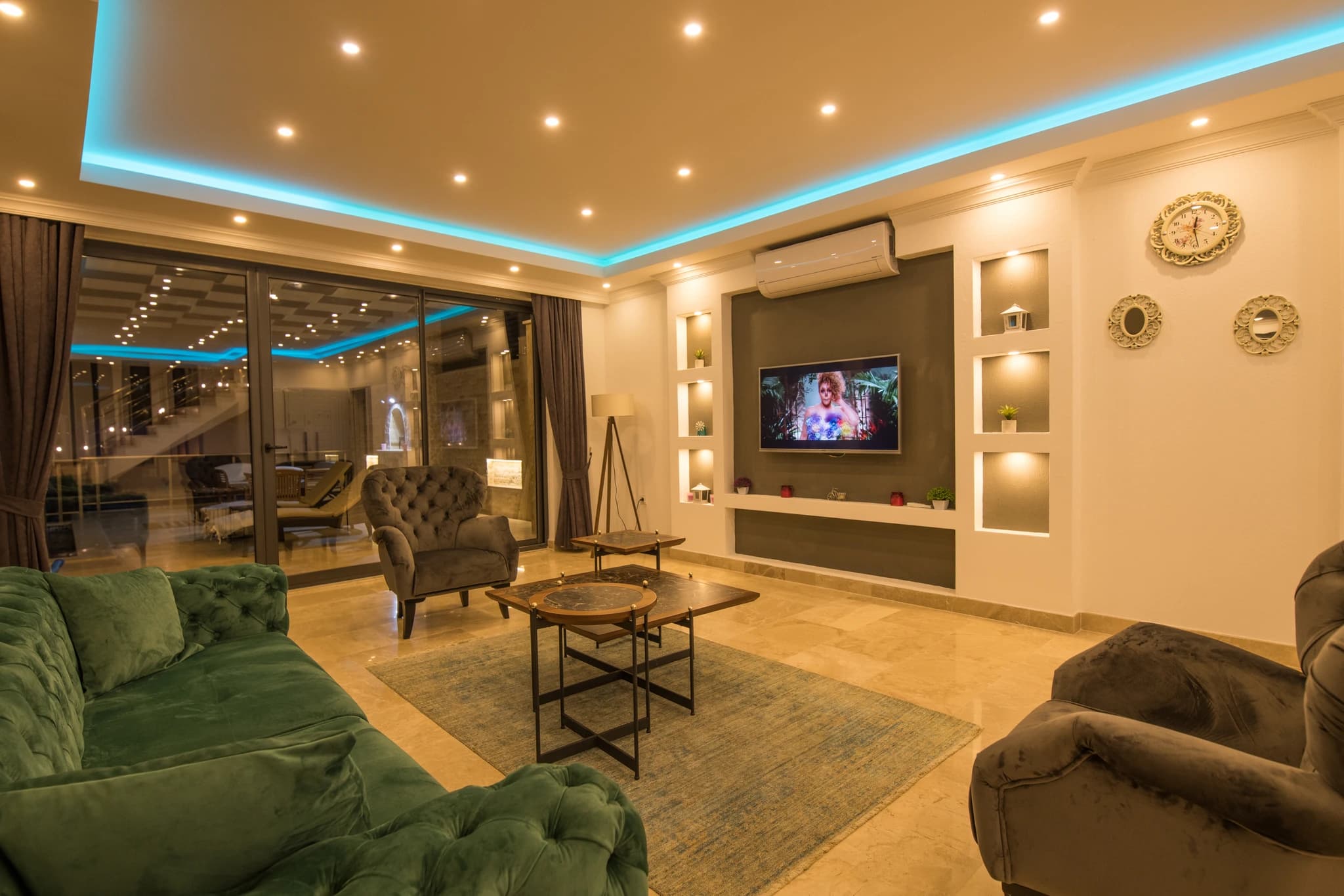 Kalkan'da Deniz Manzaralı, İç ve Dış Havuzlu Korunaklı Balayı Villası – Luxurious modern living room with plush seating, entertainment system, and ambient ceiling lighting.