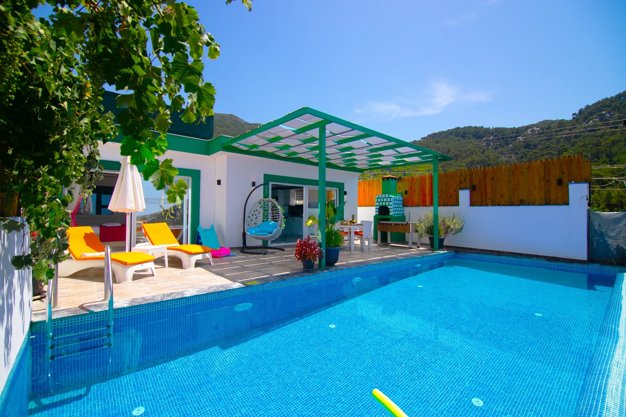 Stunning private pool with vibrant loungers, pergola, and mountain backdrop.