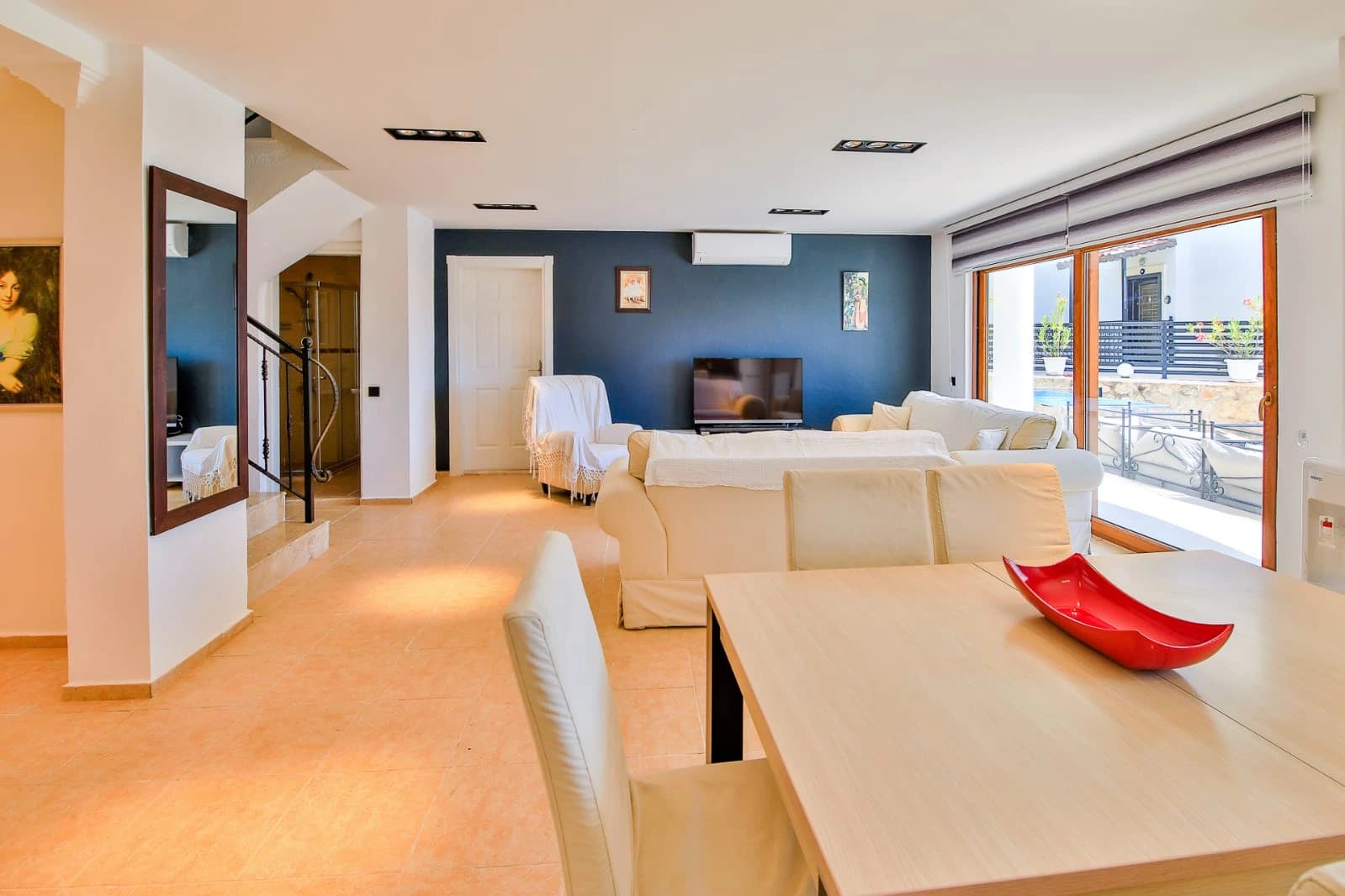 Spacious open-plan living room with cream sofas, smart TV, and direct access to a sea-view terrace.