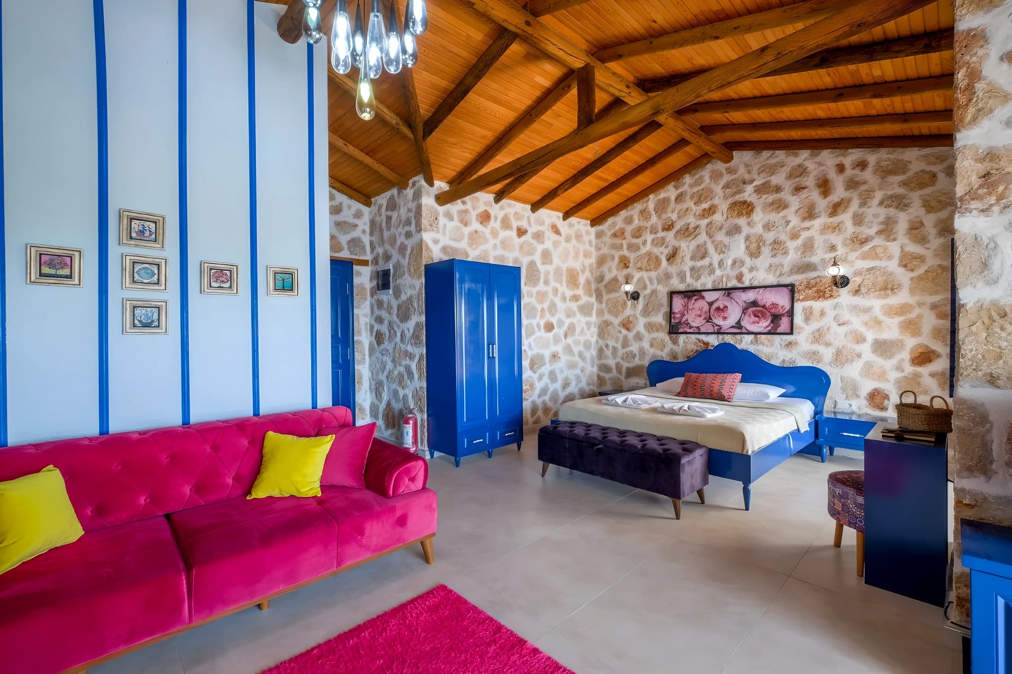 Studio-style bedroom with king bed and lounge seating in rustic stone villa.