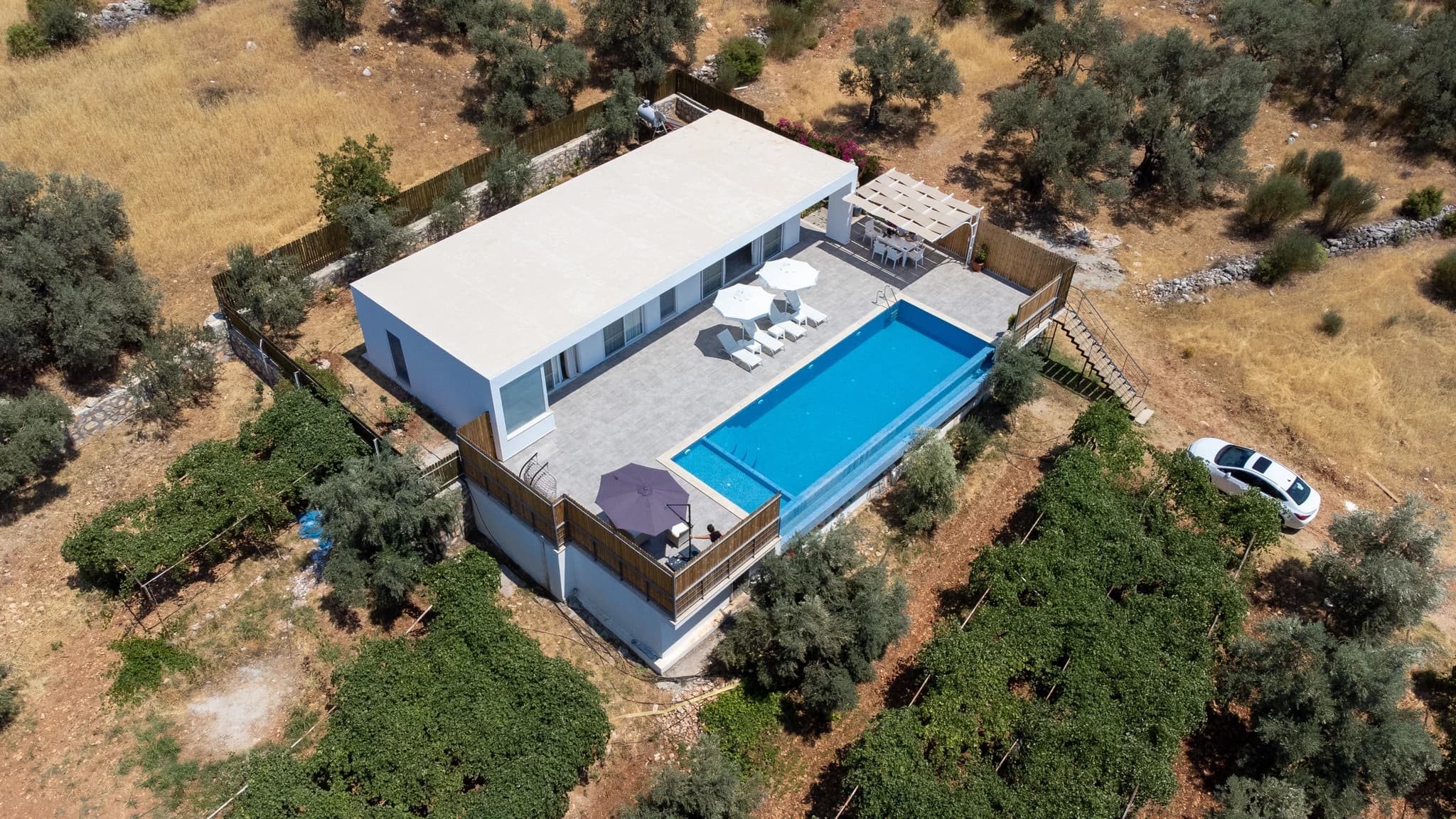 Kalkan Yakınında Sonsuzluk Havuzlu ve Dağ Manzaralı, Korunaklı 2 Yatak Odalı Villa – Elevated drone perspective showcasing the complete villa layout with pool complex and natural surroundings.