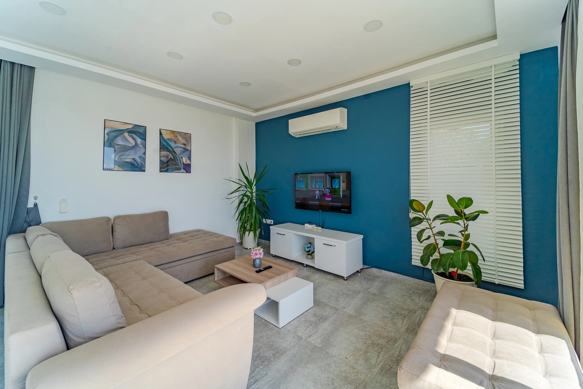 Kalkan Yakınında Sonsuzluk Havuzlu ve Dağ Manzaralı, Korunaklı 2 Yatak Odalı Villa – Modern living room with teal accent wall, comfortable sectional seating, and contemporary furnishings.