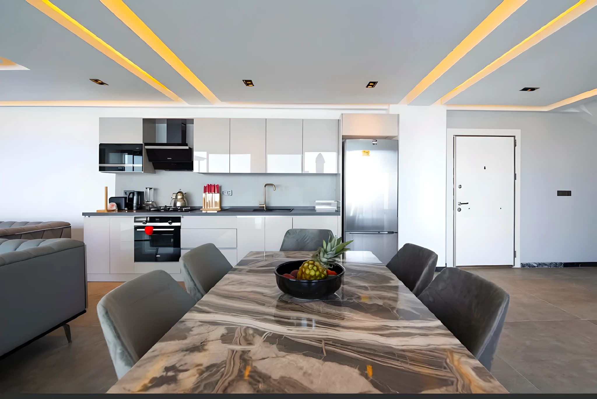 Modern open-plan dining area with marble table and integrated kitchen.
