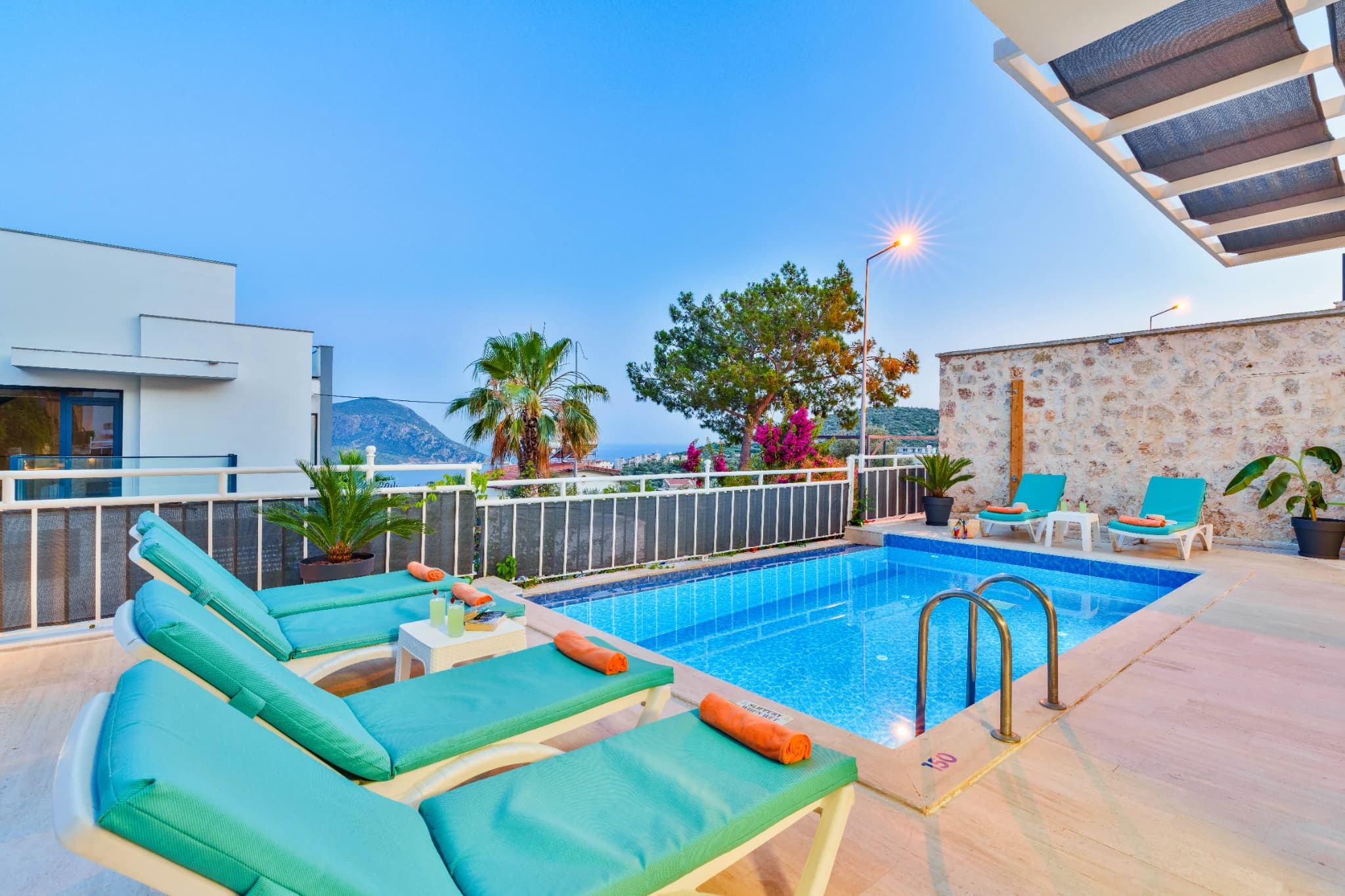 Pool deck with colorful loungers and mountain backdrop.