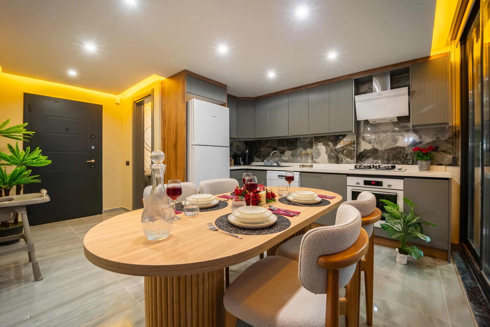 Contemporary kitchen with gas cooktop, white appliances, marble accents, and adjoining dining area.