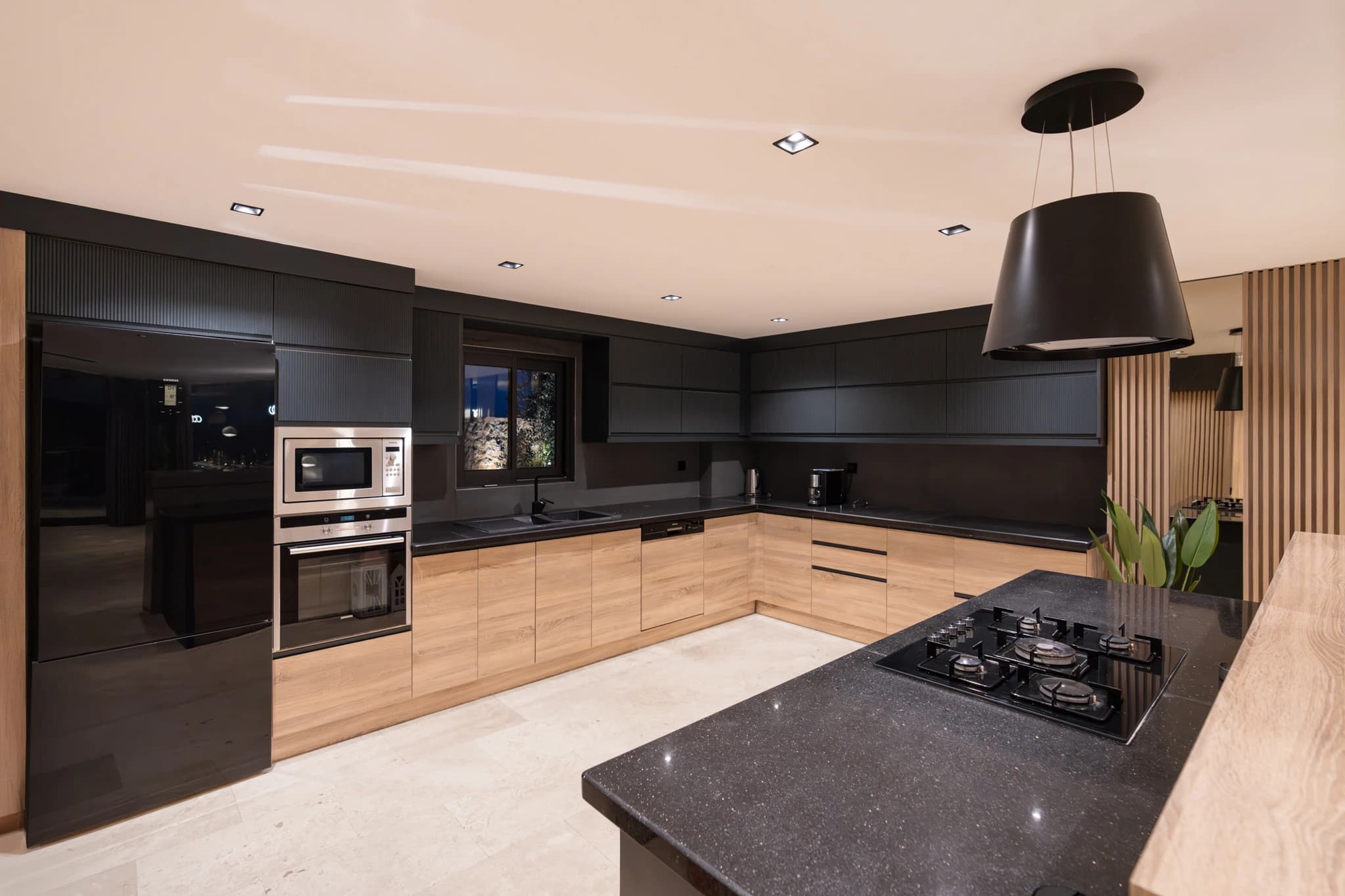 Modern kitchen featuring black cabinetry, stainless steel appliances, and large island workspace.