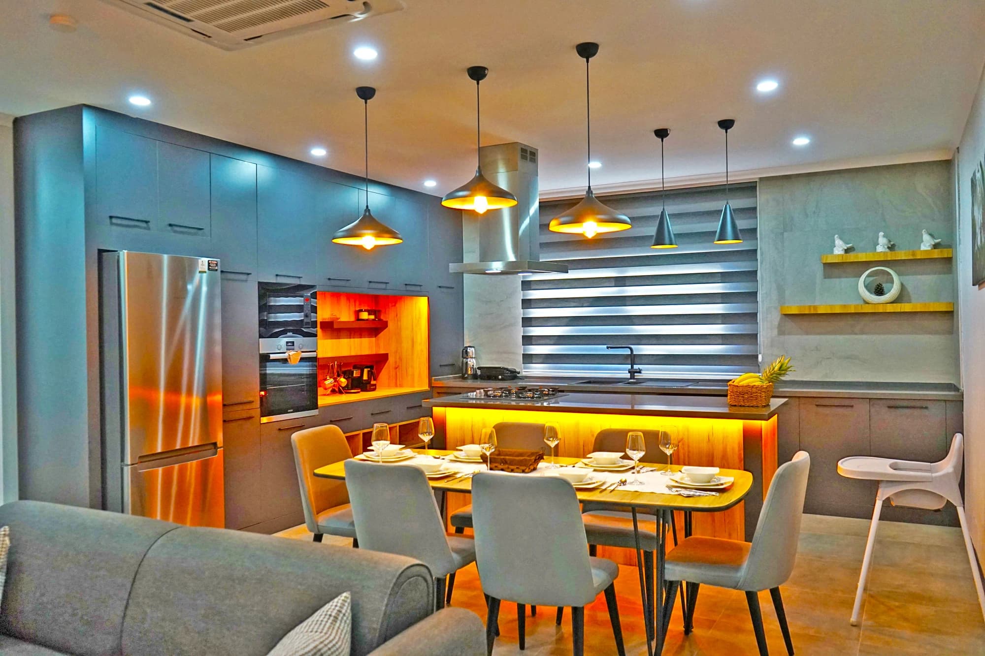 Modern open-plan kitchen and dining area with contemporary pendant lights and stainless steel finishes.
