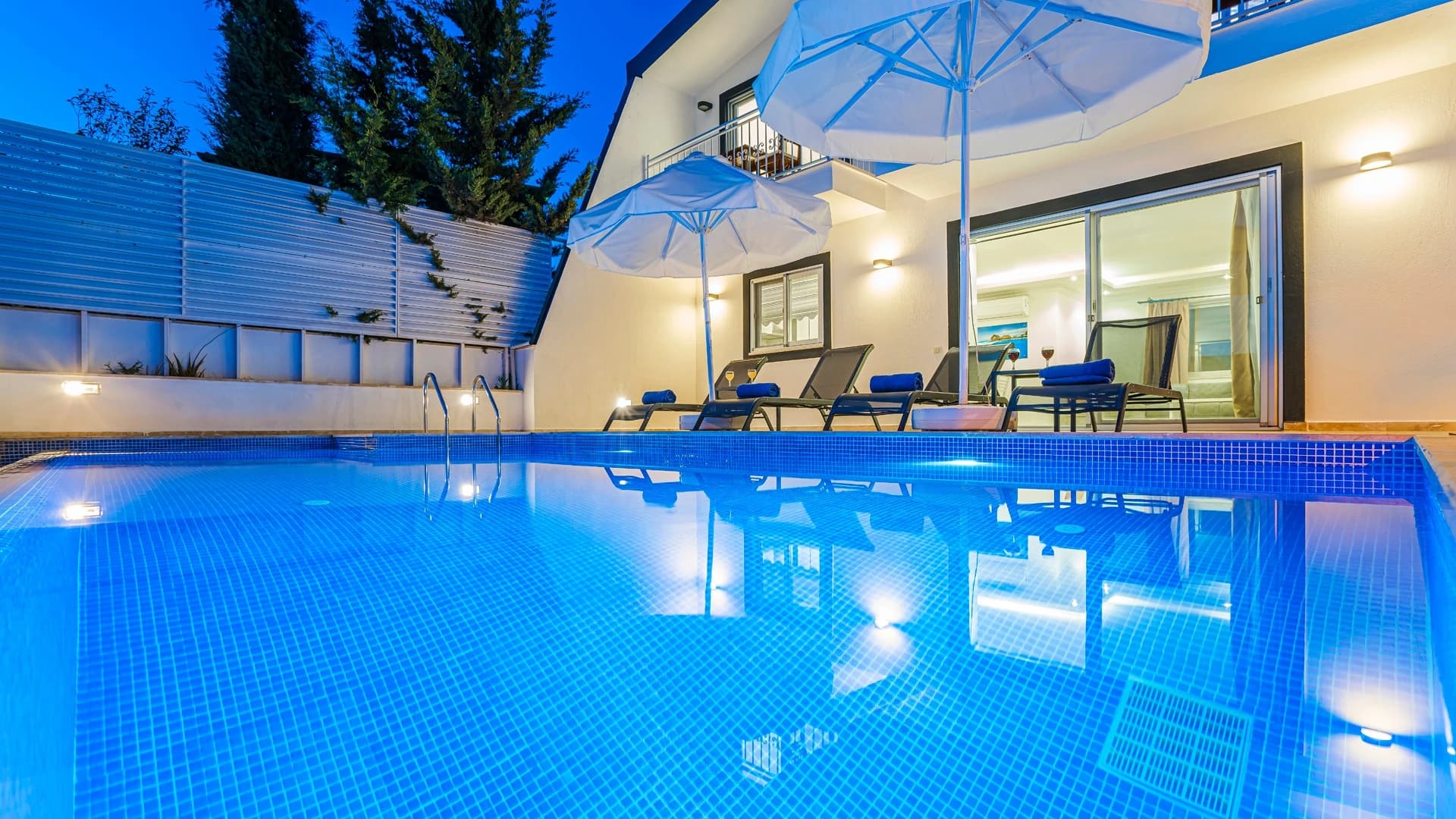 Kalkan Üzümlü'de Dağ ve Deniz Manzaralı, Isıtmalı Havuzlu, Korunaklı 2 Yatak Odalı Villa – Crystalline pool at dusk with lounge chairs and pergola shade structure overlooking the property.