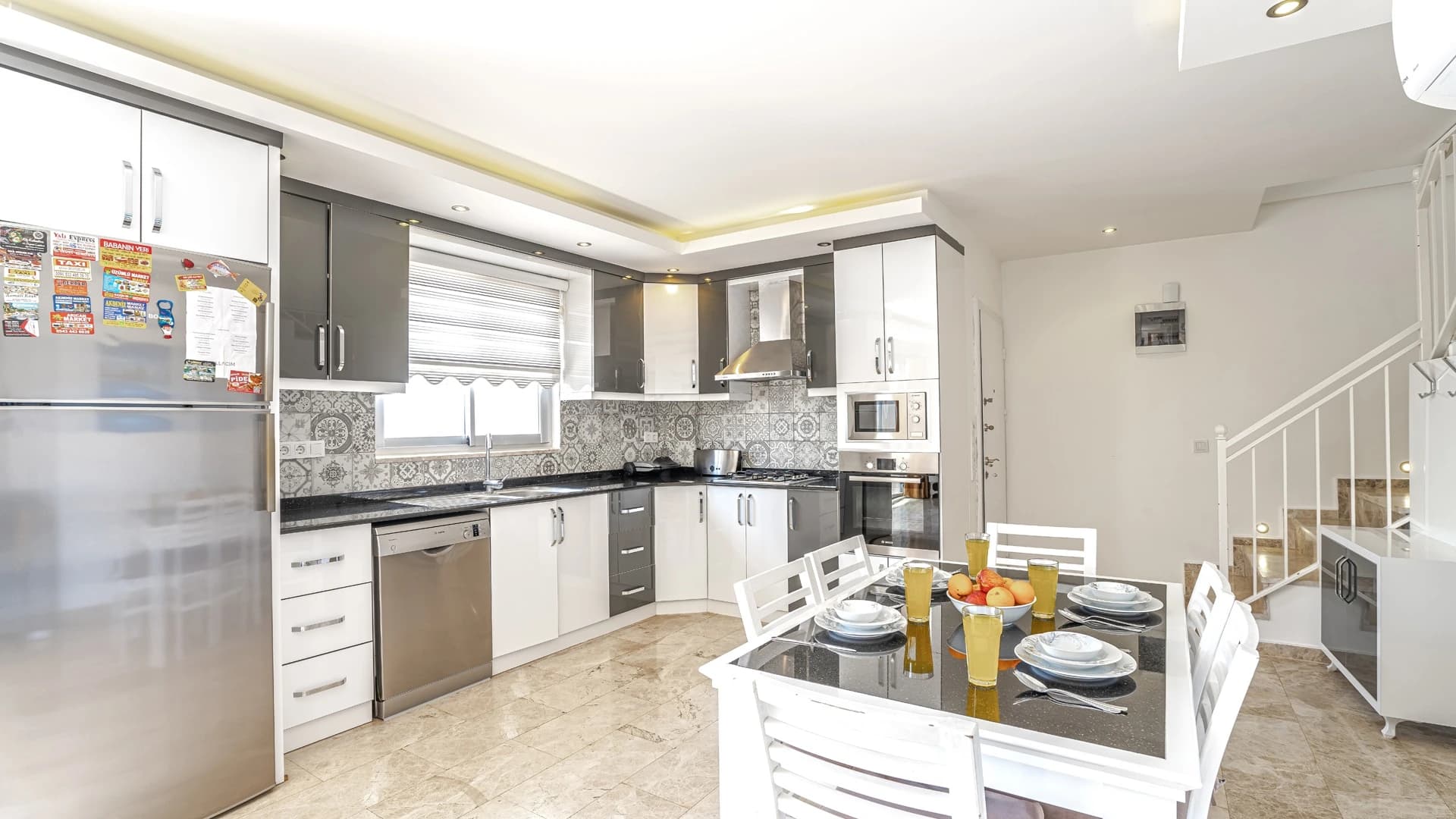 Kalkan Üzümlü'de Dağ ve Deniz Manzaralı, Isıtmalı Havuzlu, Korunaklı 2 Yatak Odalı Villa – Spacious modern kitchen with island and integrated dining area, featuring quality appliances and stylish tile work.