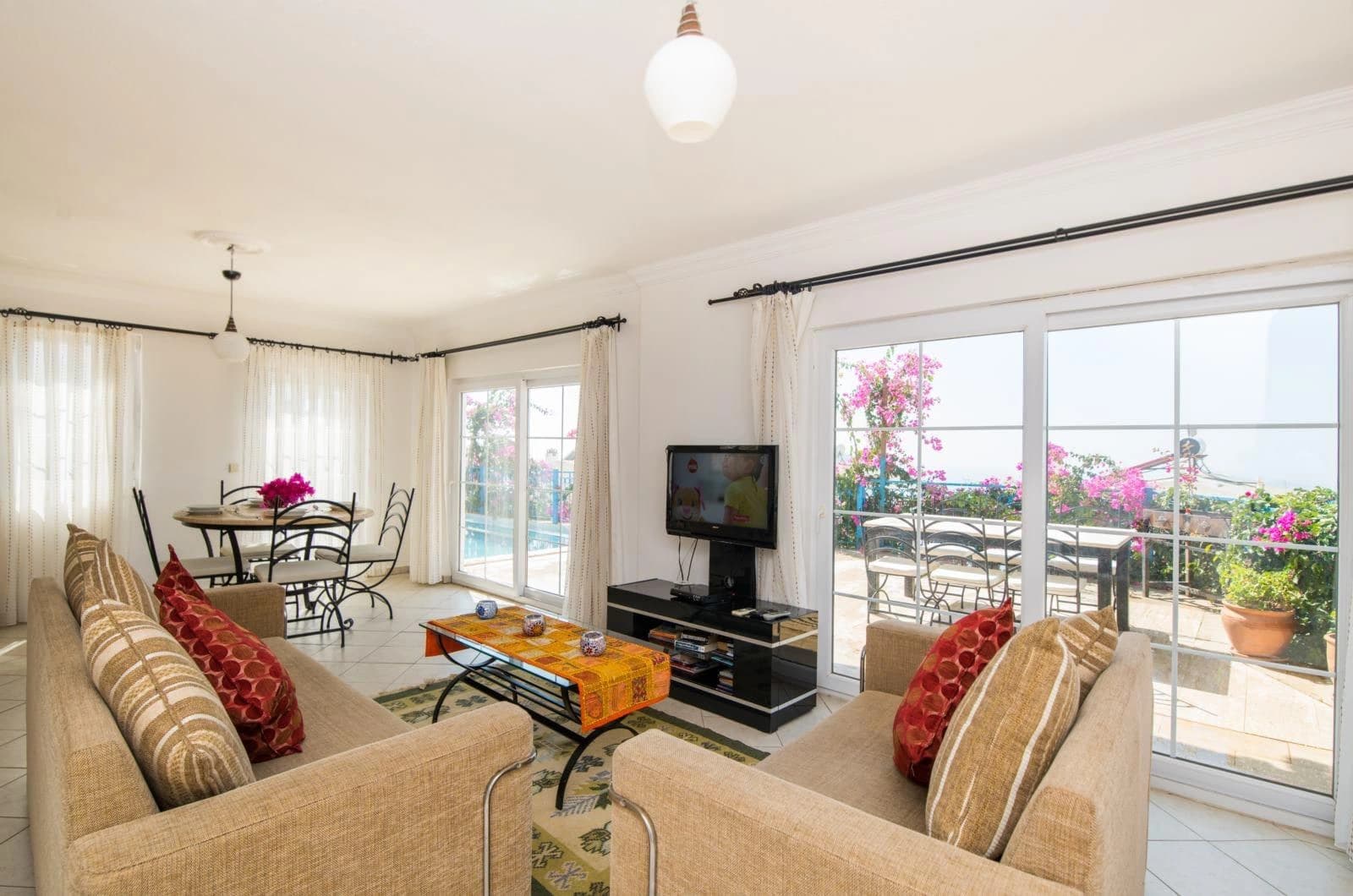 Spacious living room with sofas, TV, and panoramic sea-view doors.