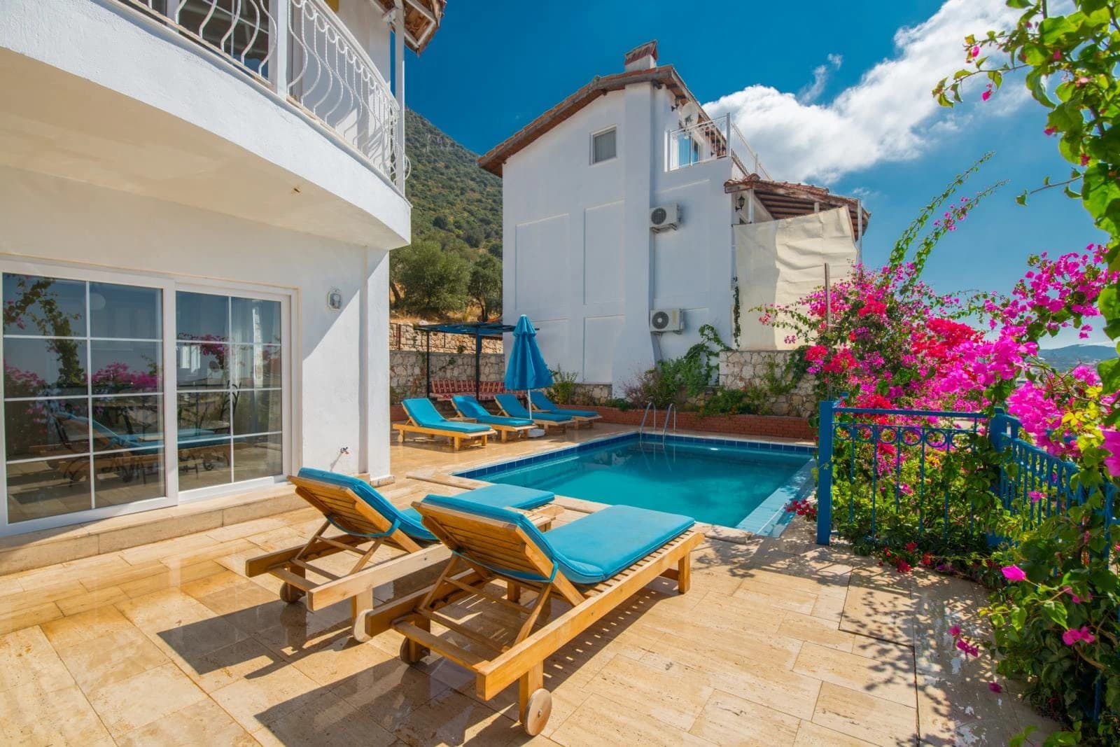 Beautiful private pool with sun loungers, flowering bougainvillea, and mountain backdrop.